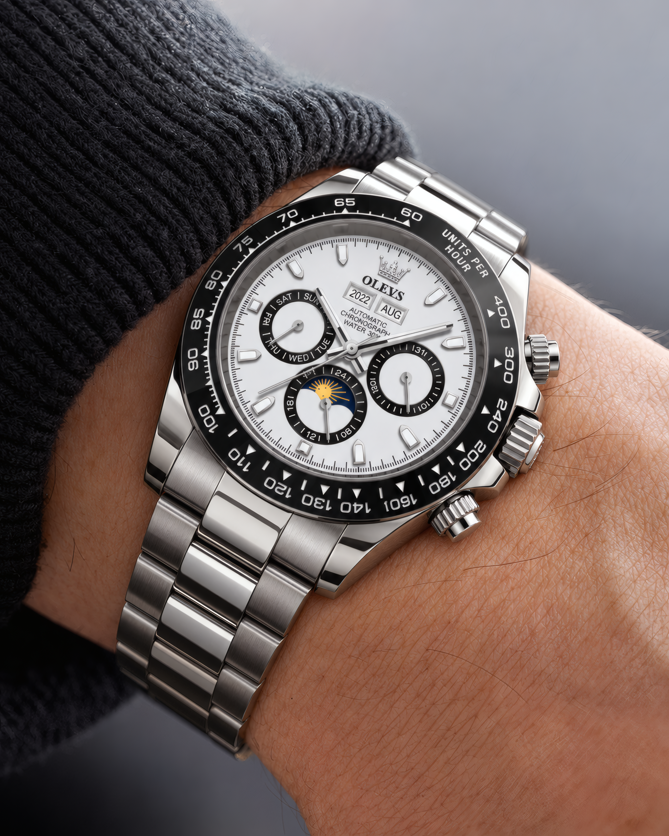 A close-up of a Rolex Daytona watch with a silver stainless steel bracelet and a white dial, worn on a person's wrist.