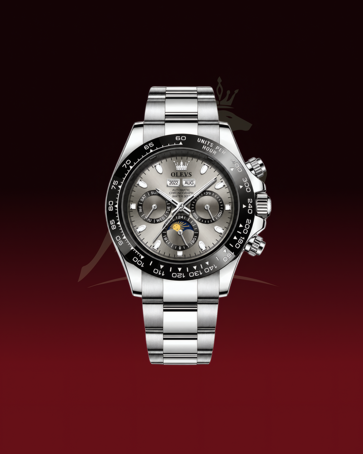 A stainless steel wristwatch with a silver-tone metal bracelet, a black bezel, and a gray dial featuring chronograph subdials and a moonphase indicator, shown against a dark red gradient background.