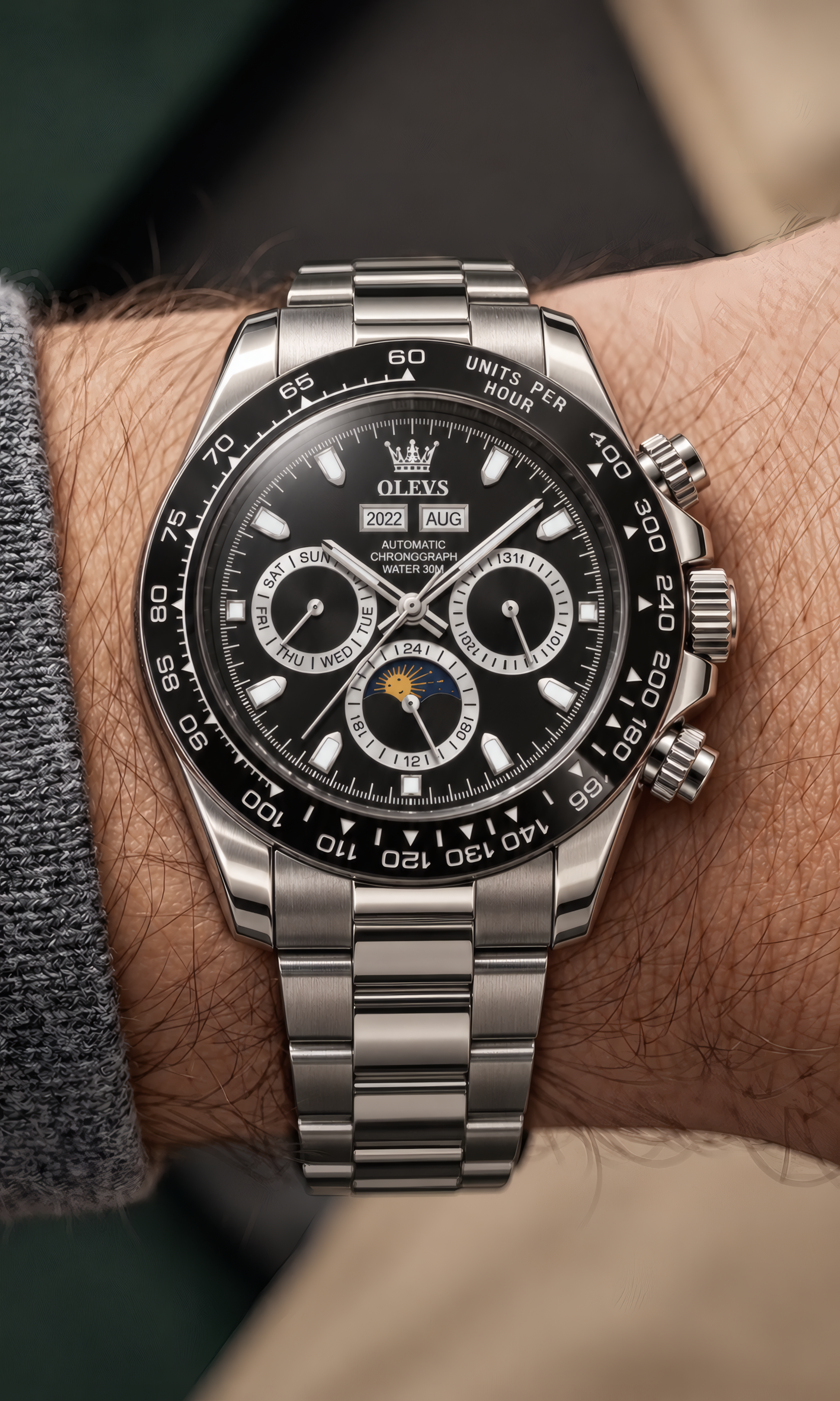 A close-up of a Rolex Daytona watch with a black dial and silver stainless steel bracelet, worn on a person's wrist.